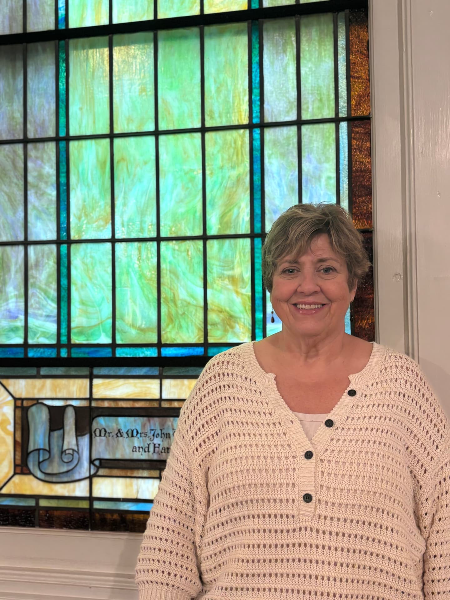 Rasita Butler in front of the stained glass window